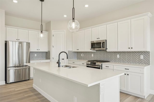 kitchen featuring a kitchen island with sink, sink, light hardwood / wood-style floors, and appliances with stainless steel finishes