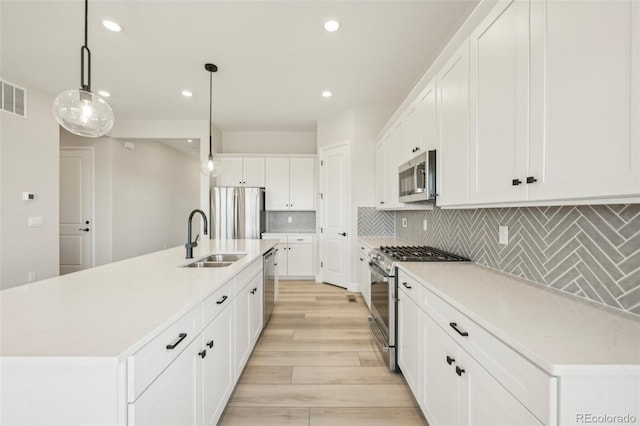 kitchen featuring pendant lighting, an island with sink, stainless steel appliances, and sink