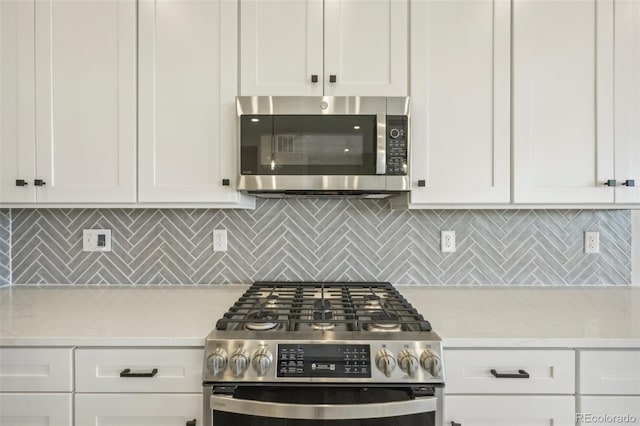 kitchen featuring backsplash, white cabinetry, light stone counters, and appliances with stainless steel finishes