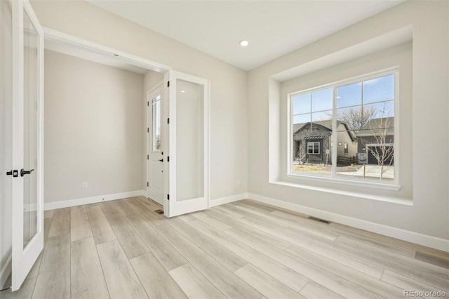 empty room featuring french doors and light hardwood / wood-style floors