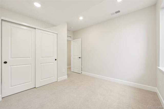 unfurnished bedroom with a closet and light colored carpet