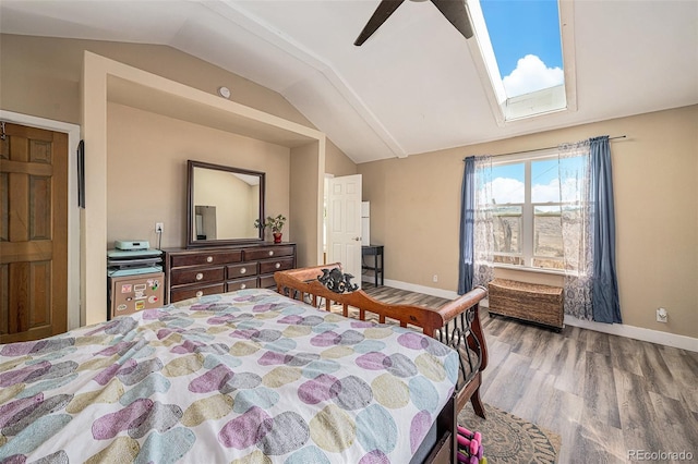 bedroom featuring ceiling fan, lofted ceiling with skylight, and hardwood / wood-style flooring