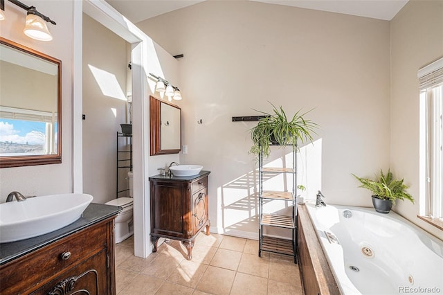 bathroom with vanity, a relaxing tiled tub, toilet, and a healthy amount of sunlight