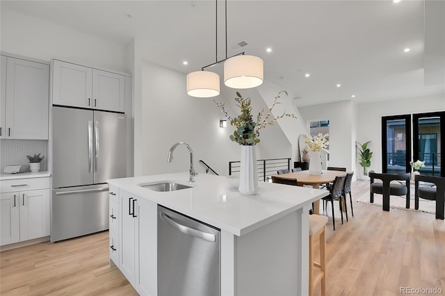 kitchen with sink, white cabinetry, tasteful backsplash, hanging light fixtures, and appliances with stainless steel finishes