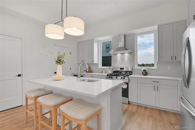 kitchen featuring sink, wall chimney range hood, pendant lighting, stainless steel appliances, and backsplash