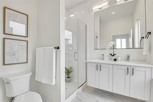 bathroom featuring a shower with door, vanity, and toilet