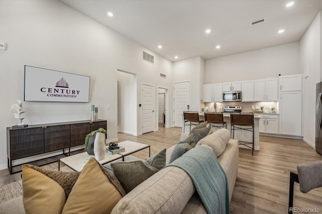 487 Interlocken Blvd Unit 106, Broomfield, CO 80021 - living room with a towering ceiling, recessed lighting, light wood-style flooring, and baseboards
