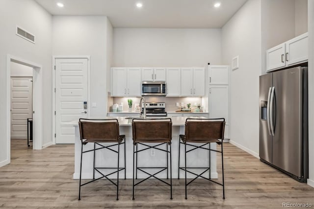 487 Interlocken Blvd Unit 106, Broomfield, CO 80021 - kitchen featuring stainless steel appliances, a towering ceiling, white cabinets, light countertops, and a kitchen breakfast bar