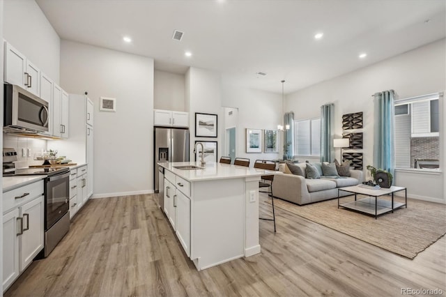 487 Interlocken Blvd Unit 106, Broomfield, CO 80021 - kitchen featuring stainless steel appliances, light wood-type flooring, a sink, white cabinets, and a kitchen breakfast bar