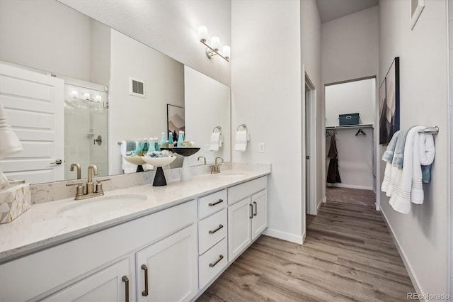 487 Interlocken Blvd Unit 106, Broomfield, CO 80021 - full bath featuring a shower stall, double vanity, wood finished floors, baseboards, and a walk in closet
