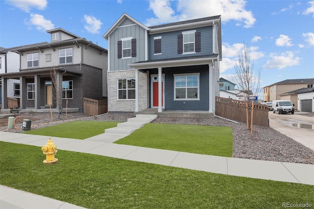 21202 E 63rd Dr, Aurora, CO 80019 - view of front of house with board and batten siding, covered porch, fence, a front lawn, and stone siding