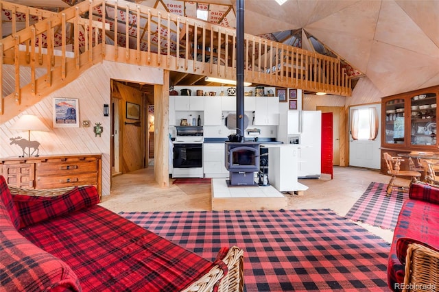 902 Hawk Way, Jefferson, CO 80456 - living area featuring a wood stove, wooden walls, light carpet, and high vaulted ceiling