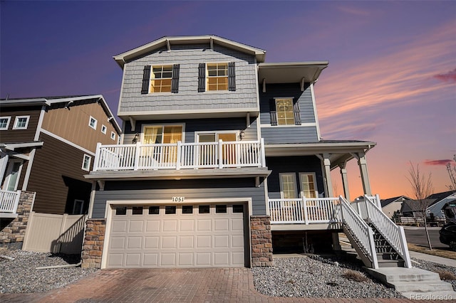 view of front of house featuring a porch, decorative driveway, an attached garage, and stairs