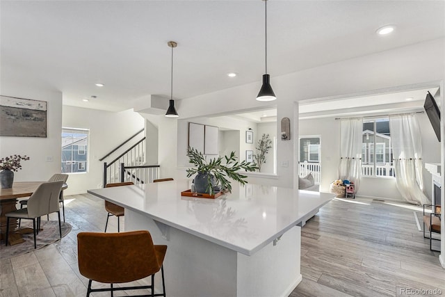 kitchen featuring light countertops, recessed lighting, light wood-style flooring, and a kitchen breakfast bar