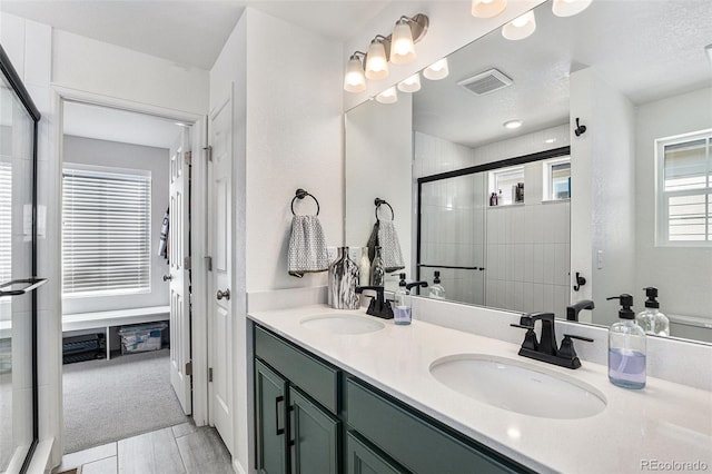 full bath featuring double vanity, a shower stall, visible vents, and a sink