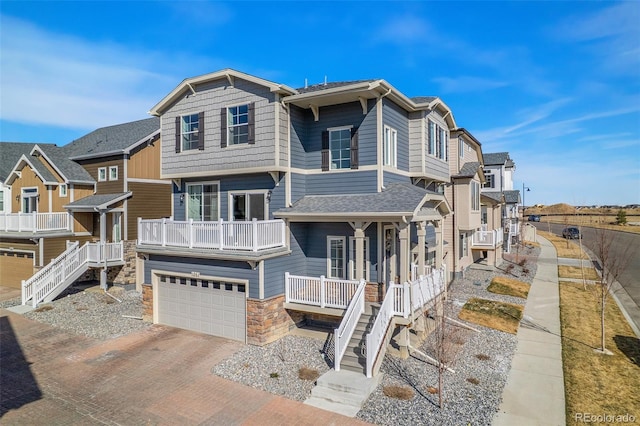 view of front facade with stairs, stone siding, decorative driveway, and a garage