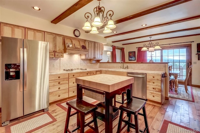 kitchen featuring beam ceiling, light hardwood / wood-style floors, hanging light fixtures, and appliances with stainless steel finishes