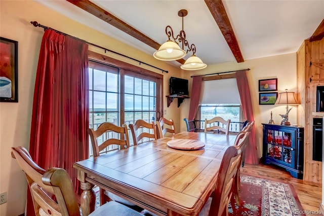 dining space with beam ceiling, a water view, and hardwood / wood-style floors