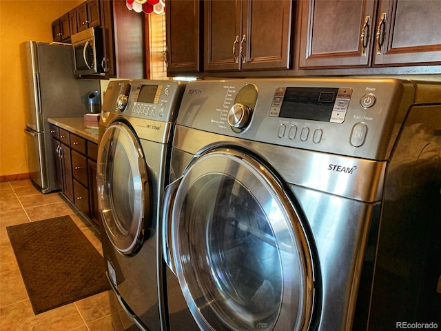 clothes washing area with cabinets, light tile patterned flooring, and washer and dryer