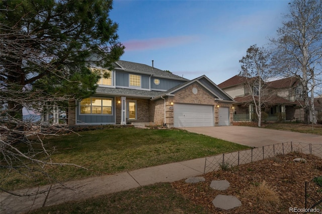 traditional-style house featuring driveway, fence, a garage, brick siding, and a yard