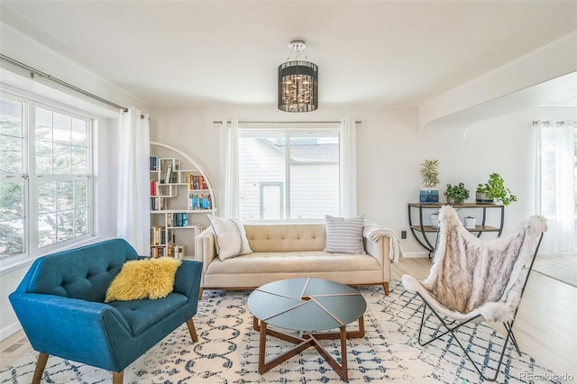 living area featuring an inviting chandelier, wood finished floors, and baseboards