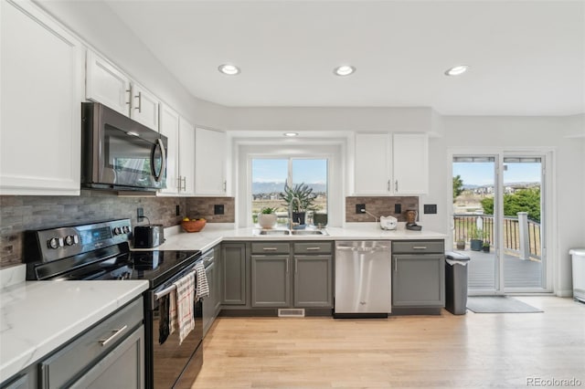 kitchen with stainless steel dishwasher, a sink, gray cabinets, range with electric cooktop, and backsplash