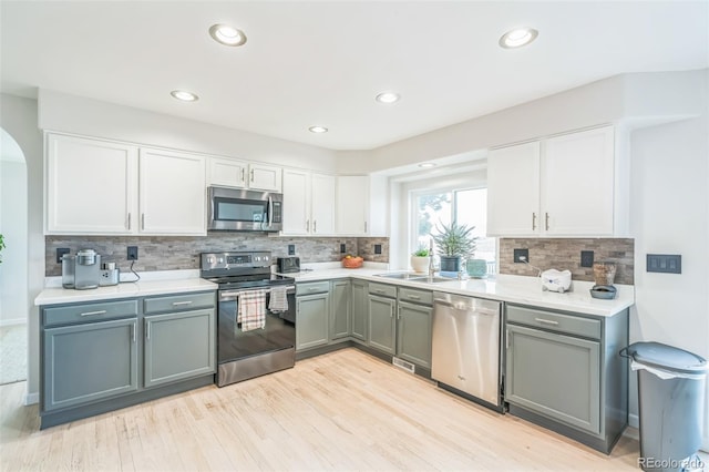 kitchen featuring white cabinets, stainless steel appliances, a sink, and arched walkways