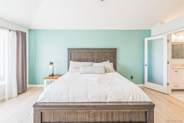 bedroom featuring light wood-style flooring, baseboards, and connected bathroom