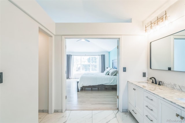 ensuite bathroom with a ceiling fan, vanity, marble finish floor, baseboards, and ensuite bath