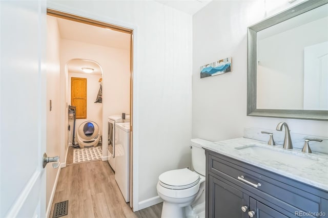 bathroom featuring wood finished floors, visible vents, toilet, vanity, and separate washer and dryer