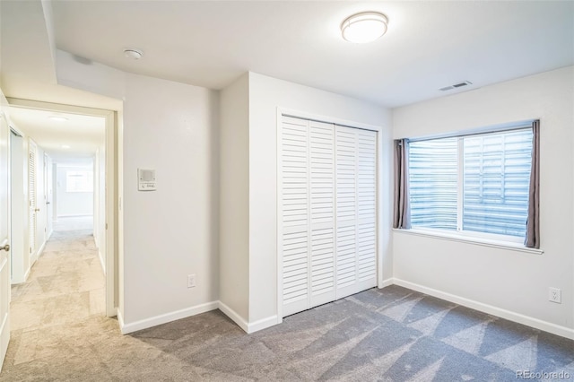 unfurnished bedroom featuring a closet, carpet, visible vents, and baseboards