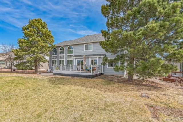 rear view of property with a wooden deck and a lawn