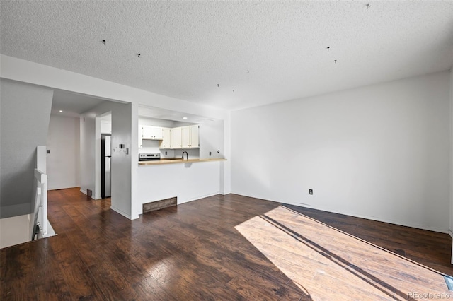 unfurnished living room featuring sink, dark hardwood / wood-style flooring, and a textured ceiling