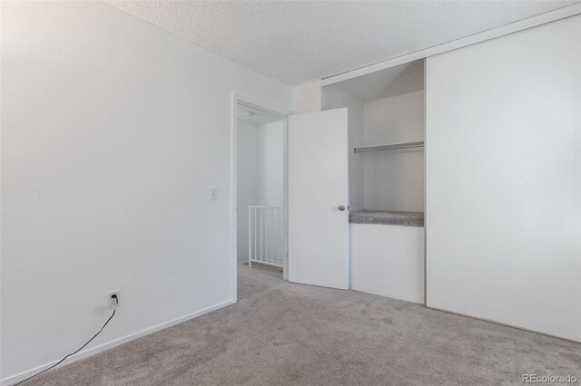 unfurnished bedroom with light carpet, a textured ceiling, and a closet