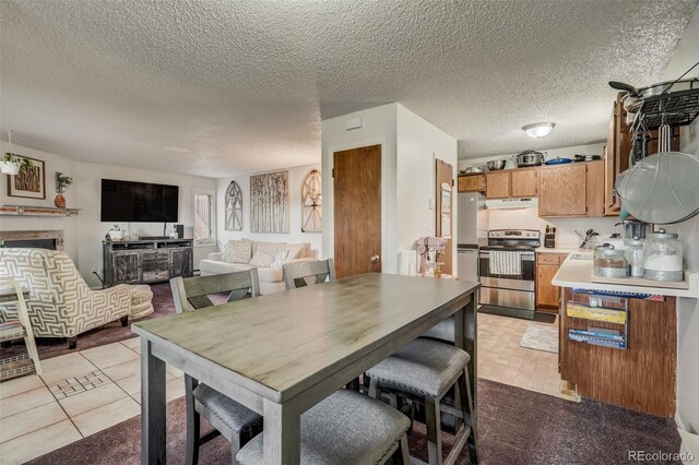 dining area with a fireplace, a textured ceiling, and light tile patterned floors