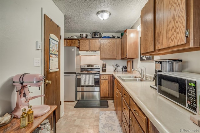 kitchen featuring sink, a textured ceiling, light tile patterned floors, and stainless steel appliances