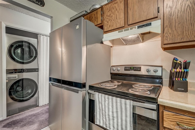 kitchen featuring stacked washing maching and dryer, dark carpet, a textured ceiling, premium range hood, and stainless steel appliances