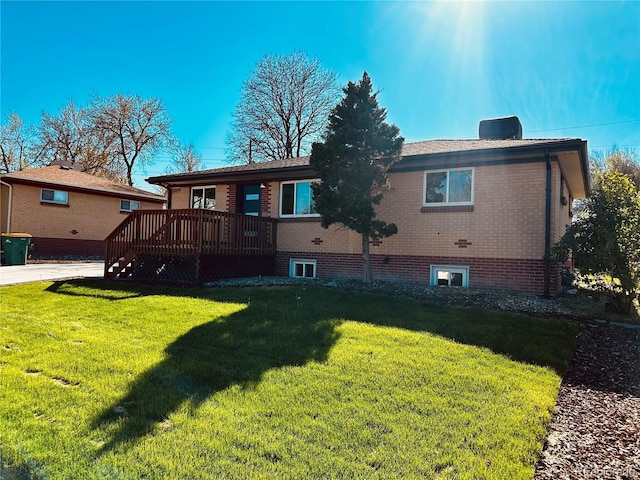 rear view of property featuring a wooden deck, a lawn, and brick siding