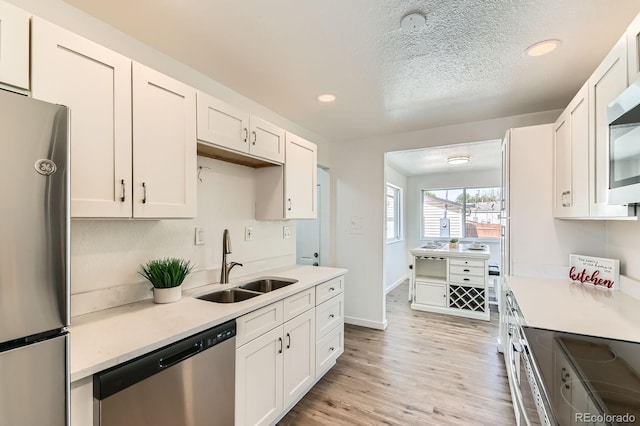 3871 Moore St, Wheat Ridge, CO 80033 - kitchen with appliances with stainless steel finishes, a sink, white cabinetry, recessed lighting, and light countertops