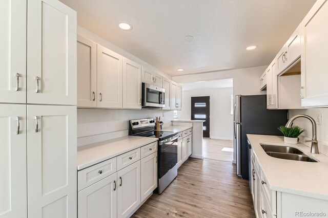 3871 Moore St, Wheat Ridge, CO 80033 - kitchen with appliances with stainless steel finishes, a sink, light countertops, light wood-type flooring, and recessed lighting