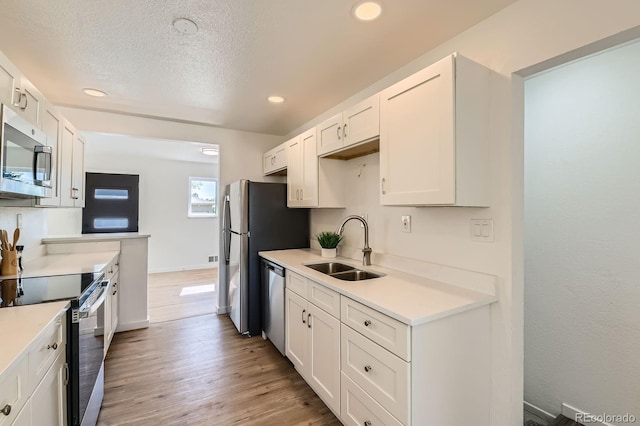 3871 Moore St, Wheat Ridge, CO 80033 - kitchen featuring appliances with stainless steel finishes, a sink, white cabinets, light countertops, and recessed lighting