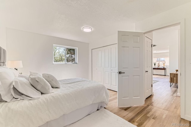 3871 Moore St, Wheat Ridge, CO 80033 - bedroom featuring light wood-type flooring, a closet, and a textured ceiling