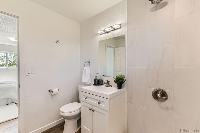 3871 Moore St, Wheat Ridge, CO 80033 - ensuite bathroom featuring vanity, toilet, a tile shower, wood finished floors, and baseboards