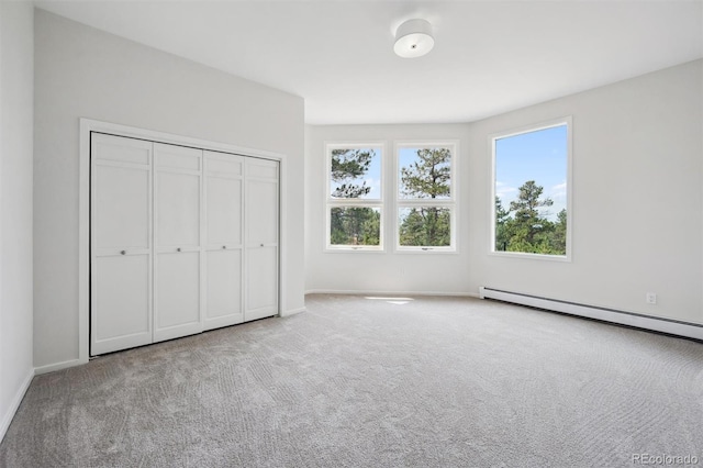 unfurnished bedroom with a closet, light colored carpet, and baseboard heating