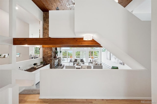 unfurnished living room with a stone fireplace, light hardwood / wood-style floors, vaulted ceiling, and wooden ceiling