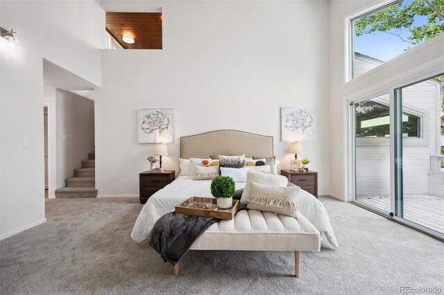 bedroom featuring a towering ceiling, access to outside, multiple windows, and carpet floors