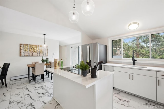 kitchen with white cabinets, stainless steel fridge, sink, hanging light fixtures, and a baseboard radiator