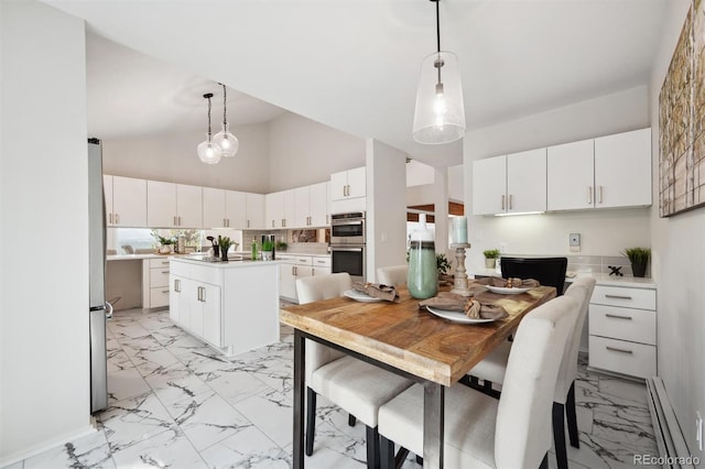 kitchen featuring light tile patterned flooring, a kitchen island, hanging light fixtures, appliances with stainless steel finishes, and high vaulted ceiling