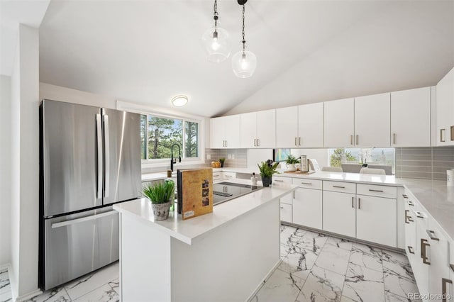 kitchen featuring light tile patterned flooring, white cabinetry, tasteful backsplash, stainless steel refrigerator, and vaulted ceiling