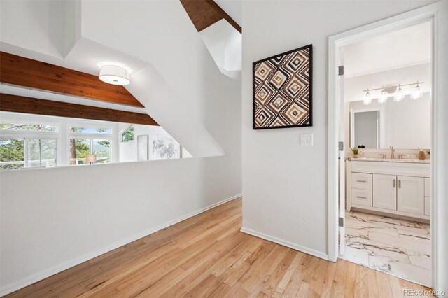 unfurnished bedroom with light hardwood / wood-style floors, sink, connected bathroom, and lofted ceiling